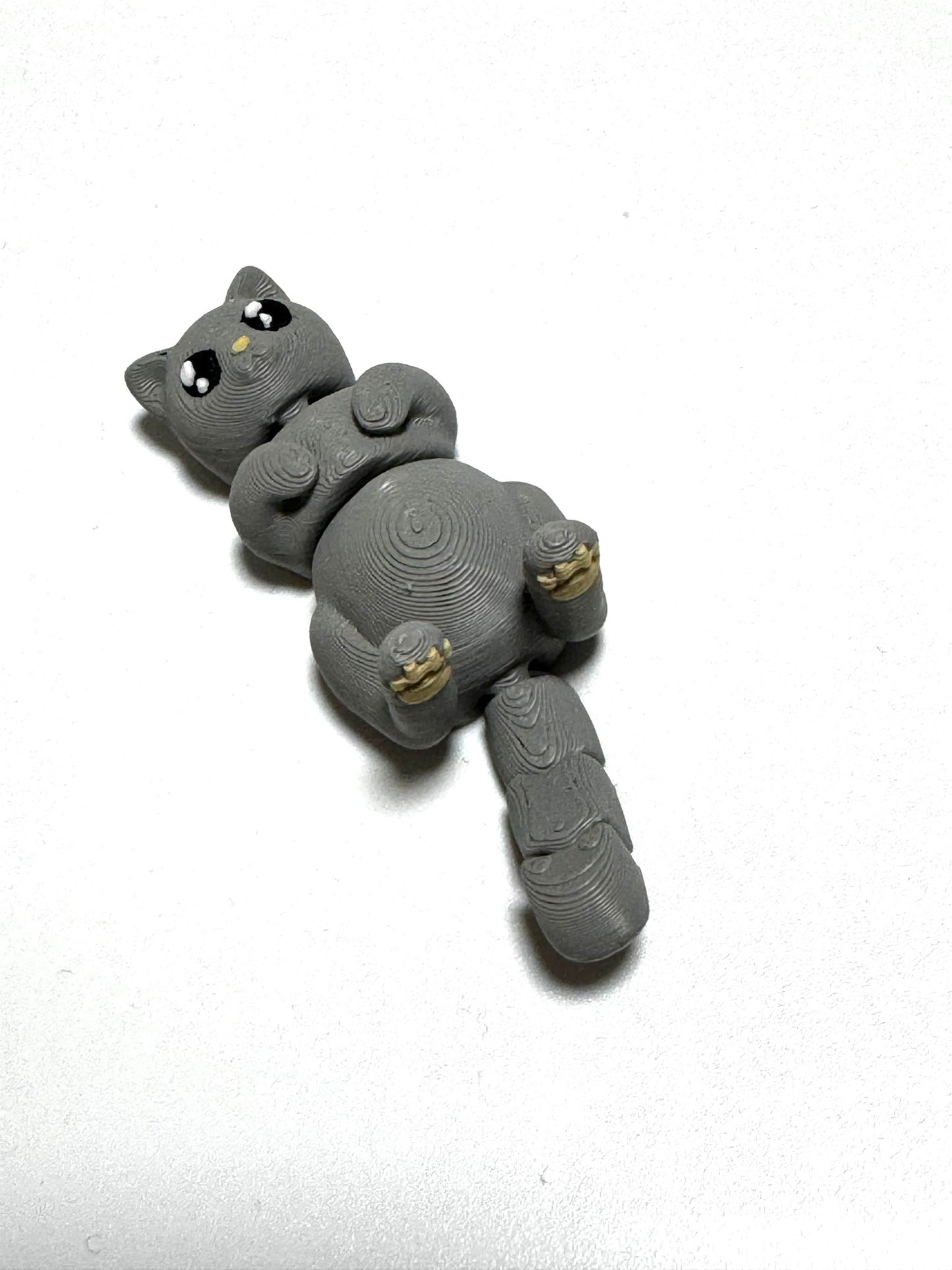 Mochi the Cat Flexling toy in black, lying on back with paws up in relaxed belly-up pose