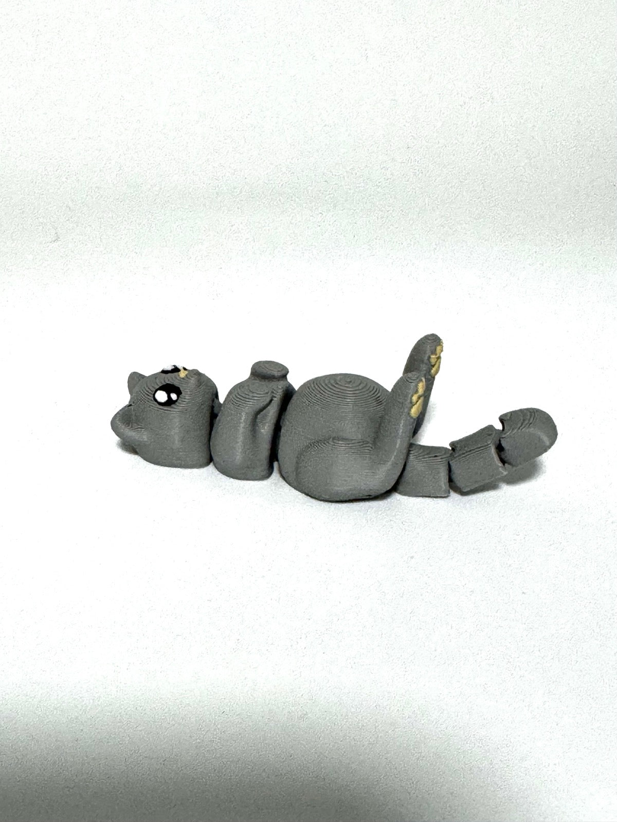 Mochi the Cat Flexling toy in black, lying on back with paws up in relaxed belly-up pose
